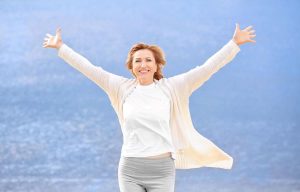 Mulher de meia idade feliz após ter realizado miniabdominoplastia.