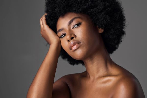 Bonita mulher negra, com cabelos black power e uma pele bem cuidada, radiante, após tratamento facial.