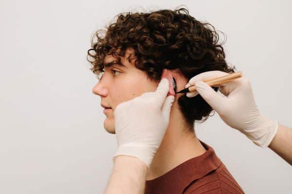 Lindo jovem tendo suas orelhas marcadas por cirurgião plástico para realizar uma otoplastia. 