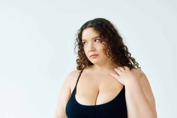 Linda mulher com excesso de peso e mamas volumosas demonstra sinal de insatisfação.