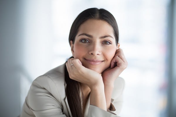 Mulher jovem de aproximadamente 30 anos, com olhos e cabelos escuros, sorrindo, posa para foto.